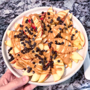 apples chopped in thin slices with thin layers of peanut butter with mini chocolate chip cookies