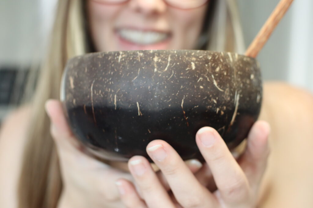 tiffany brito of tiffanybrito.com holding a coconut bowl with a smoothie inside