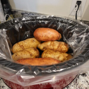 red crockpot with potatoes inside