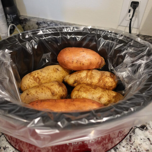 red crockpot with potatoes inside