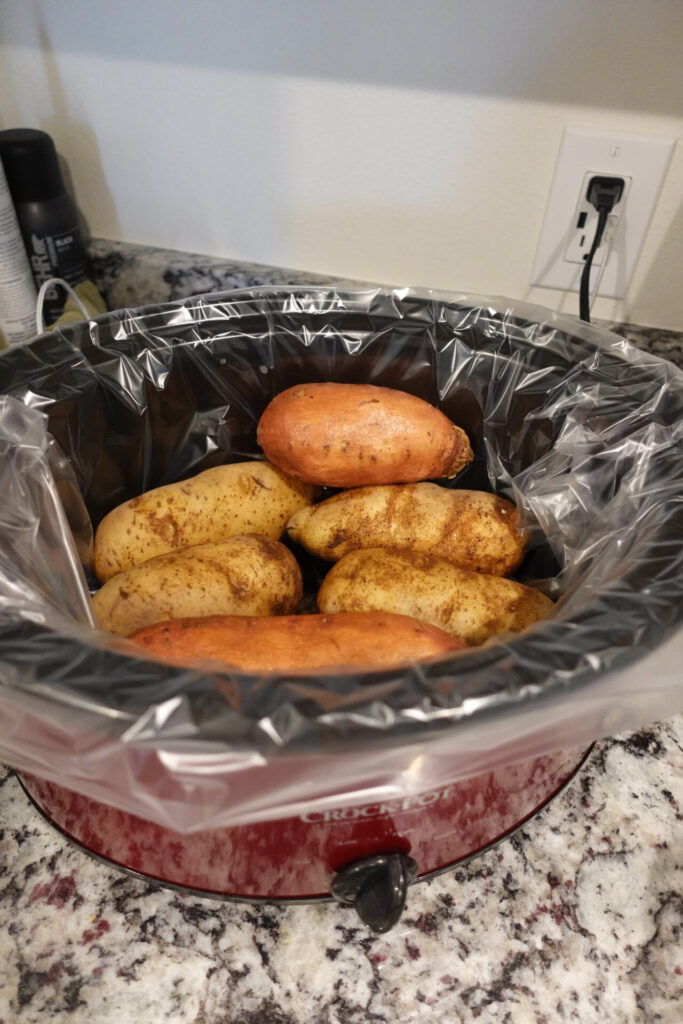 red crockpot with potatoes inside 